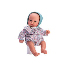 Gordi Fores doll in floral outfit and green hood, seated with visible facial features and detailed limbs.