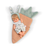 Blonde doll in floral outfit with rabbit ears hat, nestled in a carrot-shaped blanket.