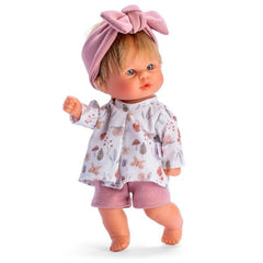 Blonde Bomboncin doll with blue eyes, wearing pink shorts, patterned shirt, and pink headband, standing in a playful pose.
