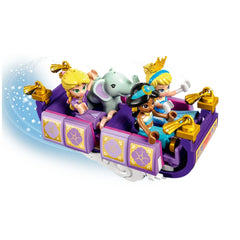 Four mini-doll figures of Disney princesses, including Cinderella and Jasmine, are seated in a colorful, decorated carriage with an elephant. The carriage has purple and gold details, and a magical sparkly effect is illustrated behind it.