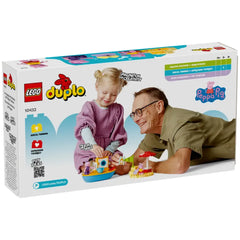 A young girl in a pink sweater and an older man with glasses smile while playing with the LEGO® DUPLO® Peppa Pig Boat Trip set, featuring vibrant pieces and characters.