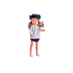 Celia doll in blue shorts and floral top, wearing a matching beret, stands with curly brown hair and friendly expression.