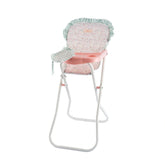 High chair for dolls with pink tray, floral cushion, and gingham bib, featuring white metal legs and ruffled edges.