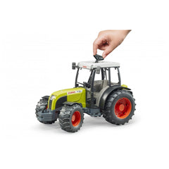 Hand adjusting the roof of a green and white Bruder Claas Nectis 267 F toy tractor with red wheels.