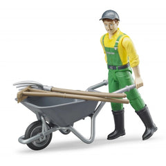 Farmer figure with yellow shirt, green overalls, black boots, holding a wheelbarrow with pitchfork and besom.