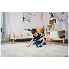 Dickie garbage truck toy with lights and sounds held by a young boy on a light beige carpet in a cozy, well-decorated room.