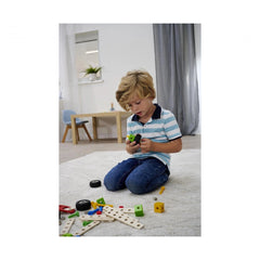 Eichhorn construction set toys with various plastic and metal components scattered around a child on a wooden table and carpe