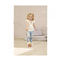 Eichhorn Duck push toy held by a smiling child on wooden floor in a cozy indoor setting.