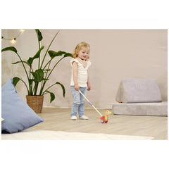Eichhorn Duck push toy held by a child indoors, surrounded by cozy home decor and soft lighting.