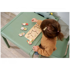 Eichhorn Puzzle Friends - A child in a sweater engaged with colorful wooden shape puzzles at a green table in a cozy room.