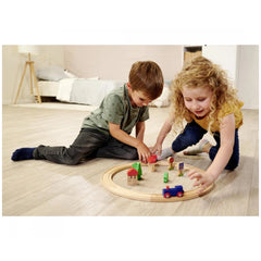 Eichhorn Train Track Playset with children playing on a wooden floor, featuring colorful trains, buildings, and trees.