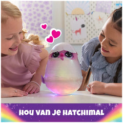Hatchimals Alive Mystery Hatch Pufficorn plush toy with lights and sounds sits on a table as two smiling girls engage with it