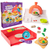 Kinetic Sand Squish Pizza play set featuring an orange toy oven, red pizza, and purple spatula and cutter on a white surface.