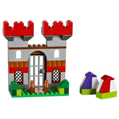 Large gray and red LEGO castle with two towers, a central door, and decorative windows. Two colorful rocks nearby.