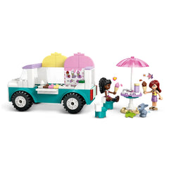 Colorful Lego Friends ice cream truck with pink and yellow toppings, two minidolls enjoying ice cream at a table, and a bunny figure nearby.