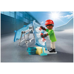 PLAYMOBIL Glazier figure in red helmet and green shirt, holding a blue bucket, set against a blue and white wall.