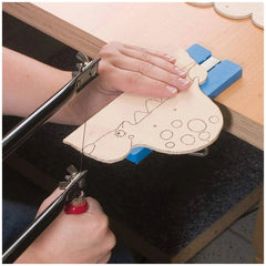 Hands using a fretsaw to cut a dinosaur shape in wood, part of the Prebaro Fretwork Kit.