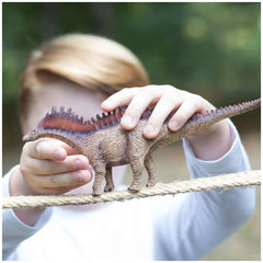 Amargasaurus toy dinosaur held by a child, featuring a spiked back and vibrant colors in an outdoor setting.
