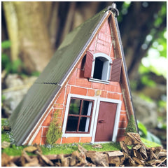 Teifoc Finnish hut features a red brick facade, wooden door, and corrugated metal roof, surrounded by green grass and rocks.