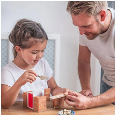 Teifoc Fire Station craft set being used by a man and a girl, focused on building with red bricks at a wooden table.