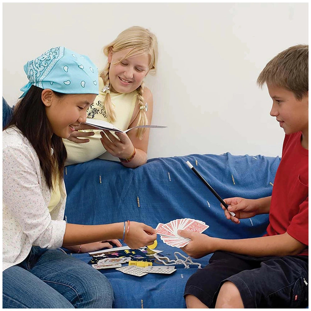 KidzLabs Magic Kit being enjoyed by two children and an adult on a blue fabric couch with glossy playing cards.