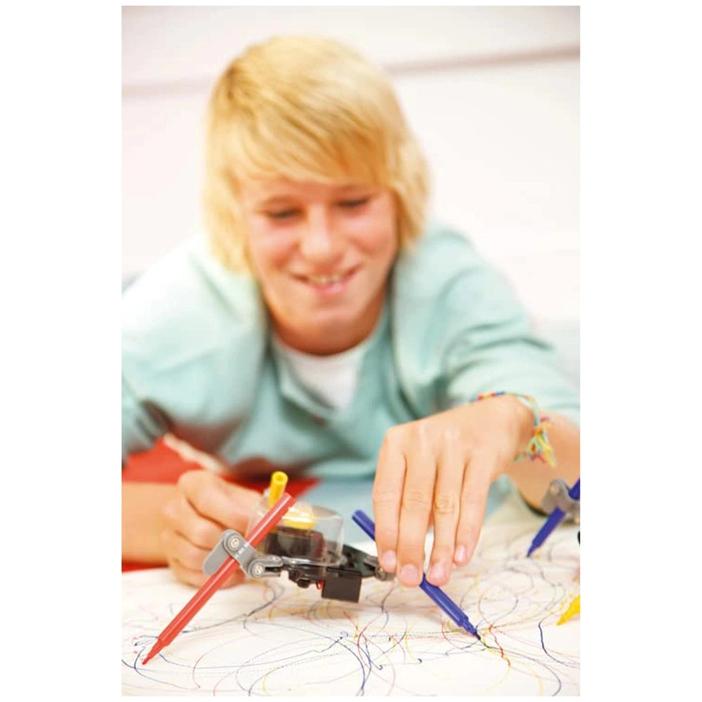 KidzRobotix Doodling Robot showcased with a person holding red and blue pencils, sitting on a red surface in front of scribbl