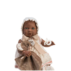 Lara Reborn doll in a floral dress with bonnet, holding a brown blanket and pacifier, seated against a white background.