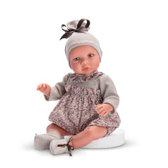 ASI Dolls Leo Romper from Martina Collection, 46 cm, with floral outfit and hat, expressive eyes, seated on a white surface.