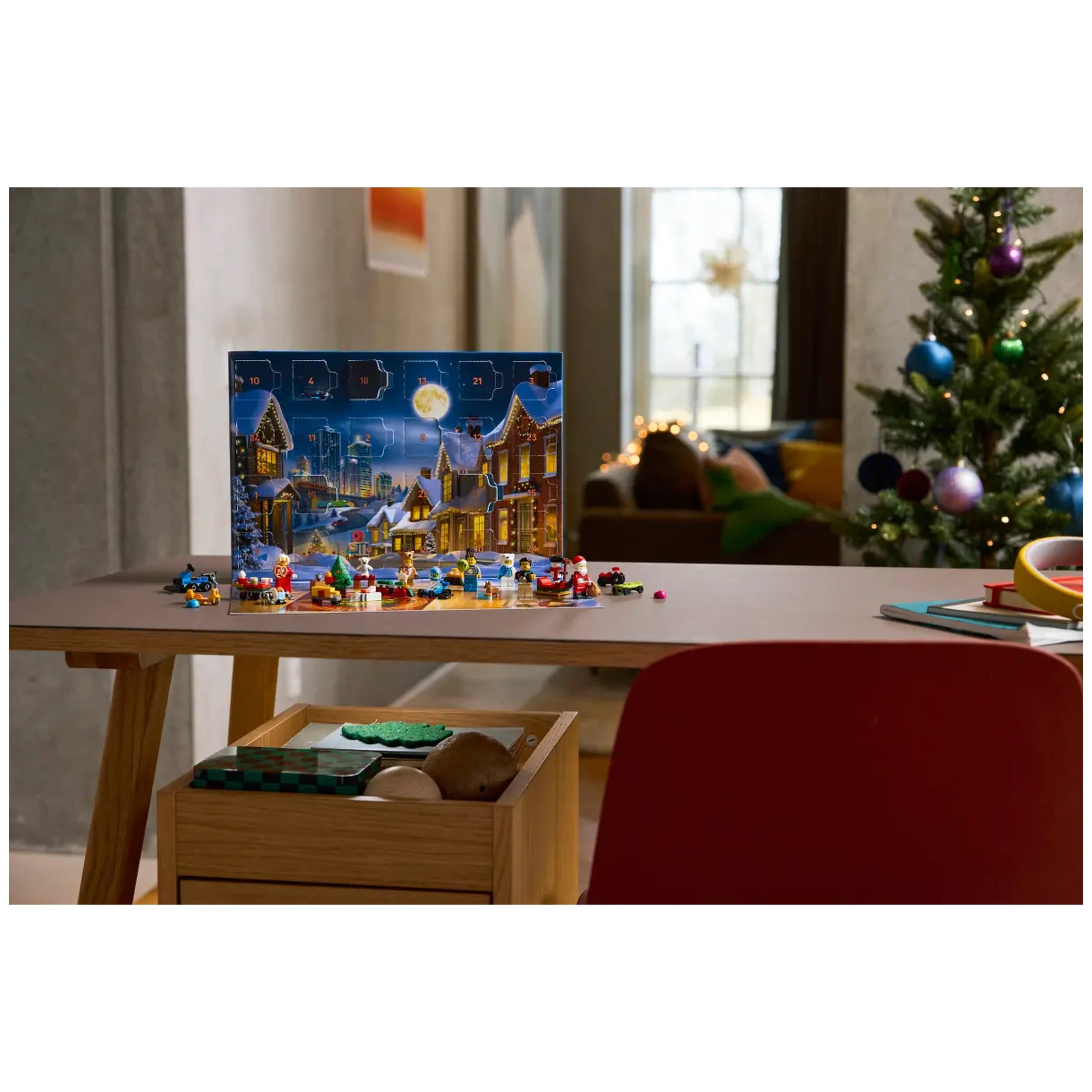 LEGO City Advent Calendar 2025 displayed on a wooden table, featuring festive mini builds and a holiday scene backdrop, with a Christmas tree and cozy room in the background.