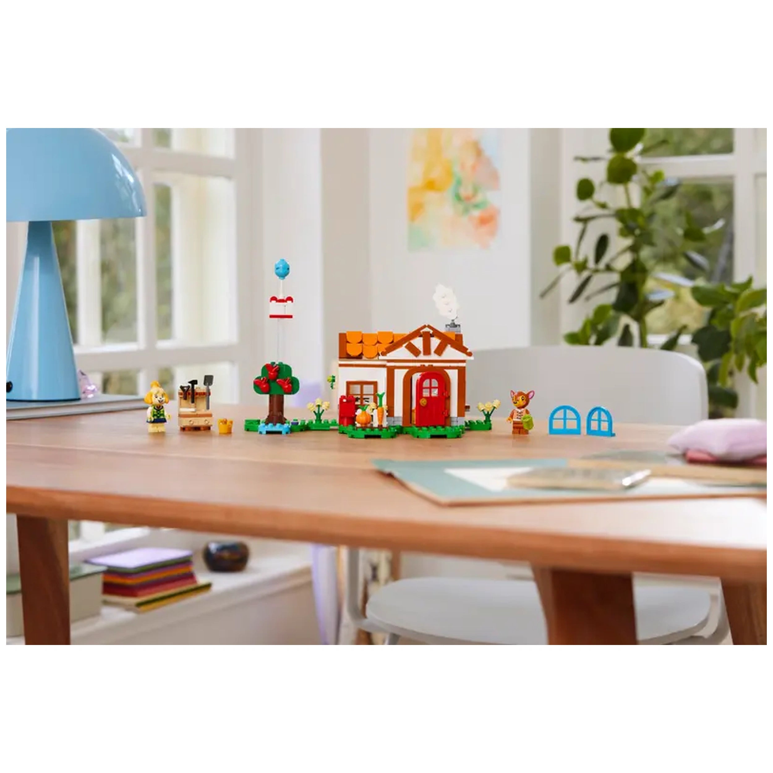 LEGO® Animal Crossing™ construction set featuring Isabelle's vibrant house with red doors, surrounded by trees and playful characters.