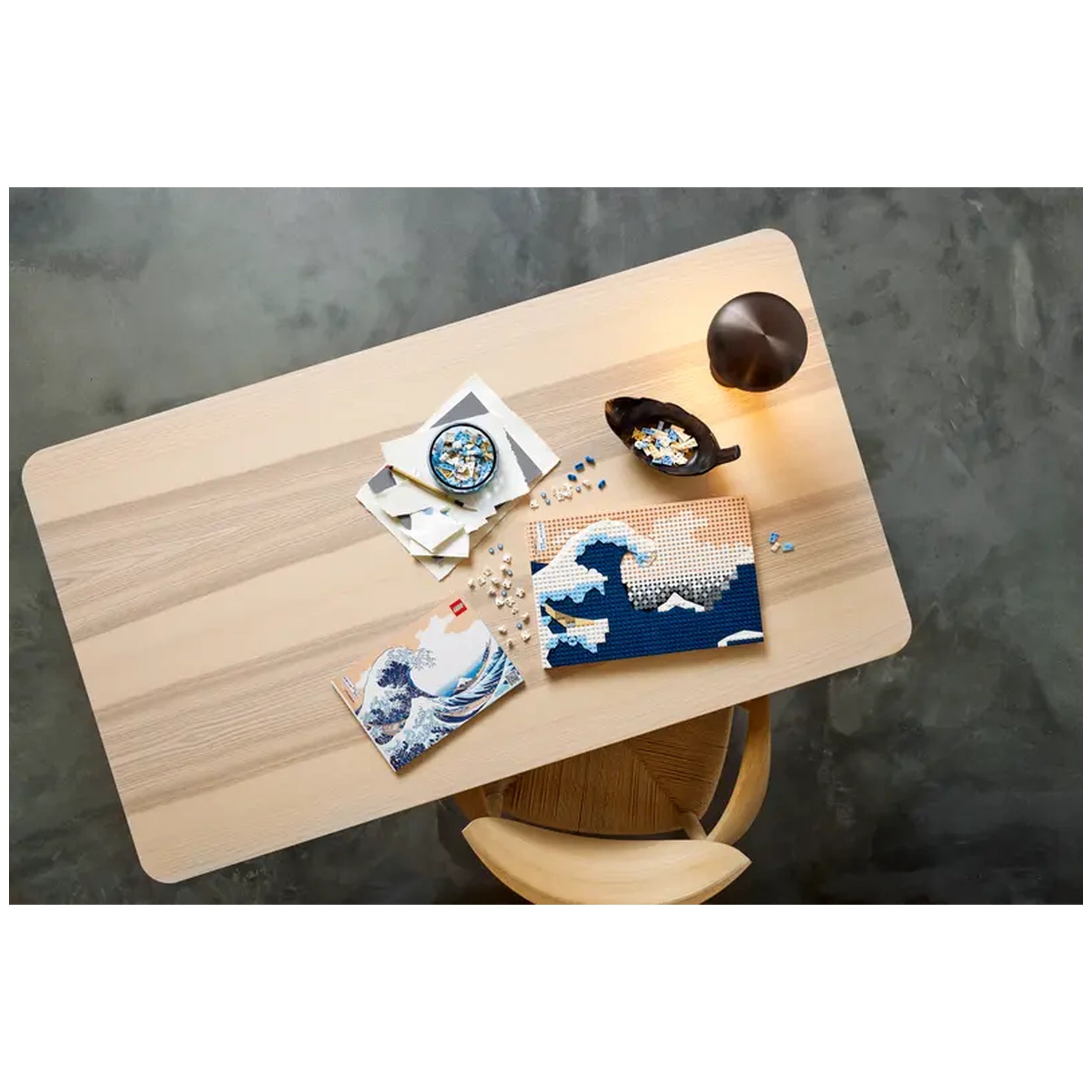 LEGO® Art set featuring Hokusai's The Great Wave, spread out on a wooden table, with pieces and instructions beside a decorative bowl.