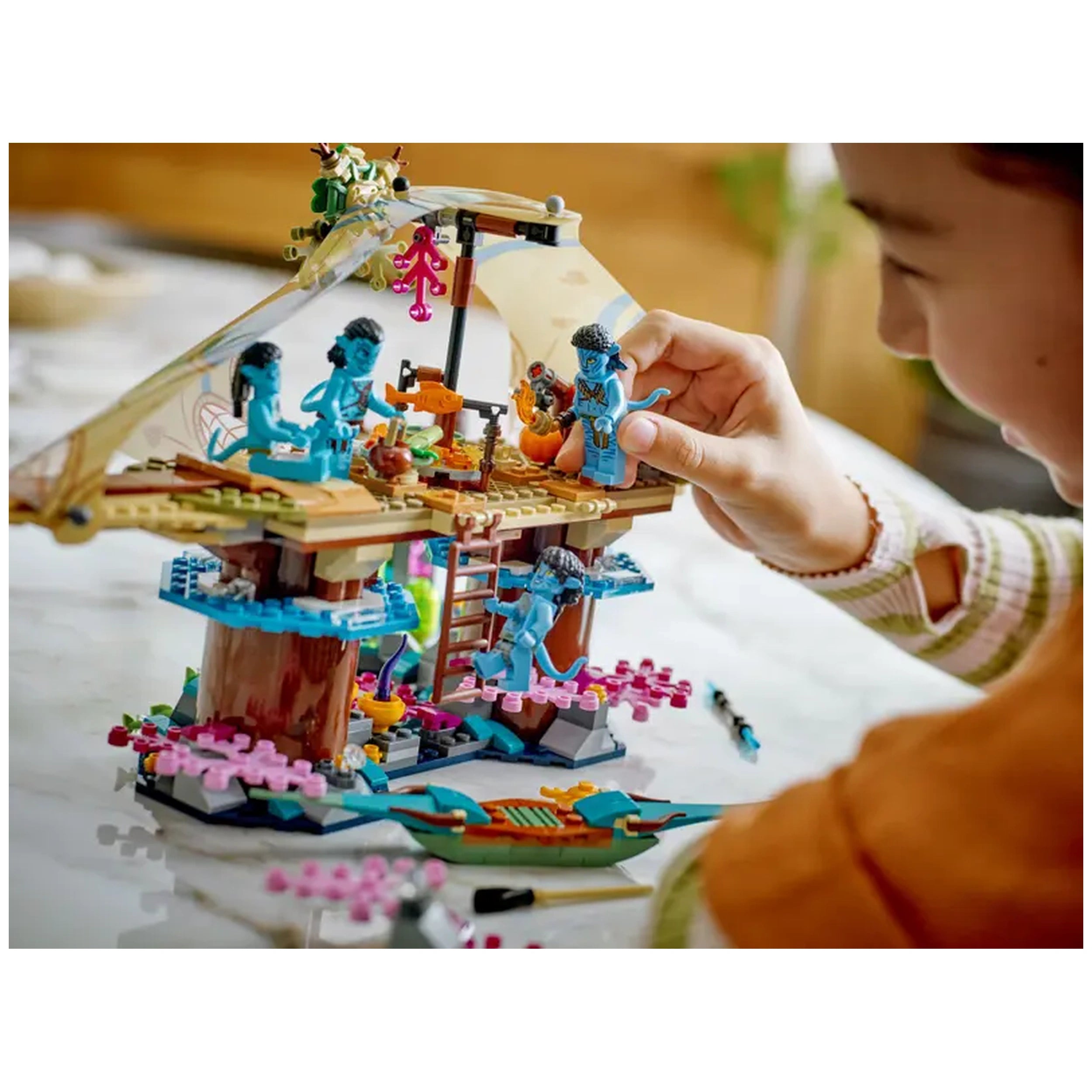 Young child assembling the LEGO Avatar Metkayina Reef Home set, featuring vibrant blue characters against a colorful, detailed backdrop.