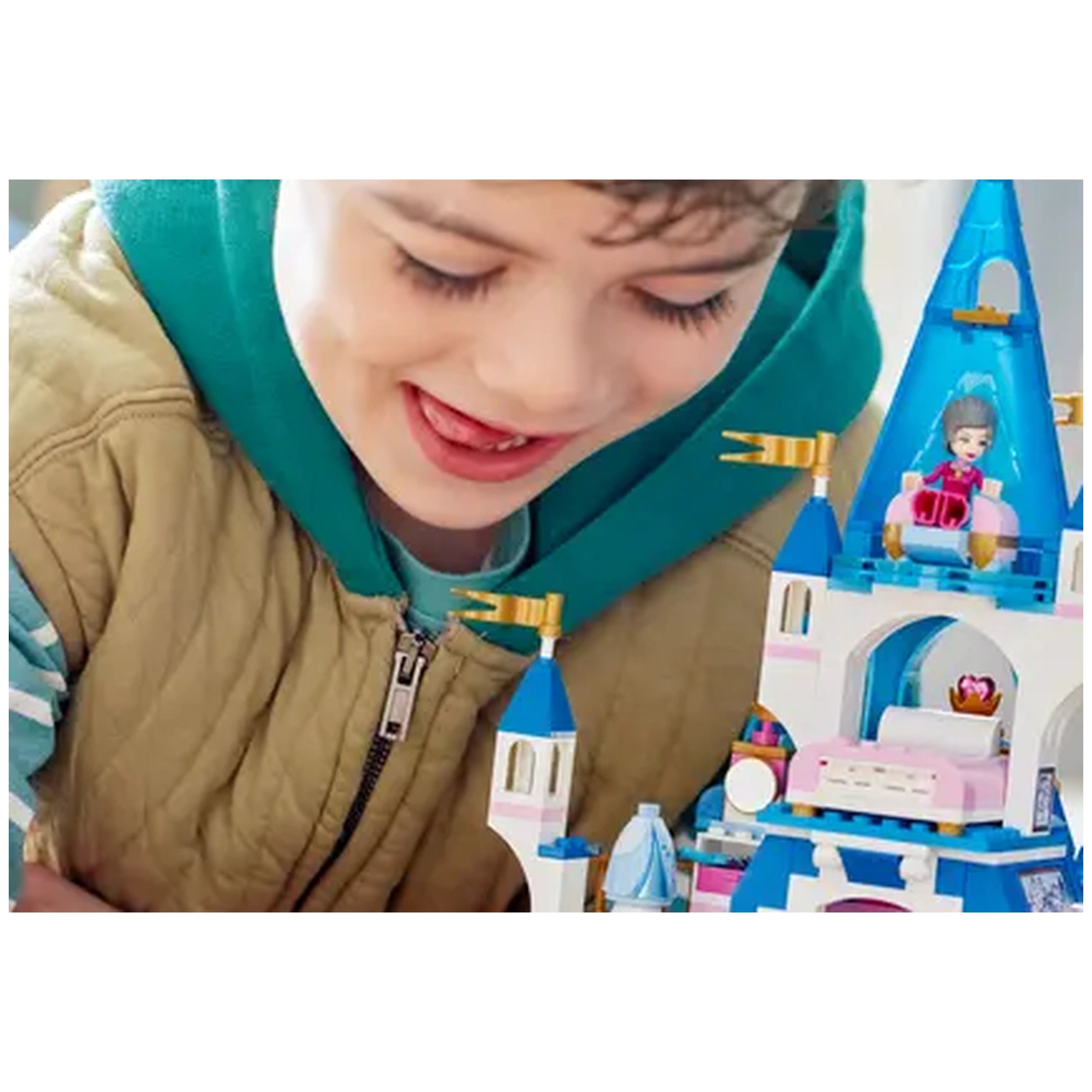 A joyful child concentrates on building LEGO® Disney Cinderella and Prince Charming’s Castle, featuring colorful towers and figures.