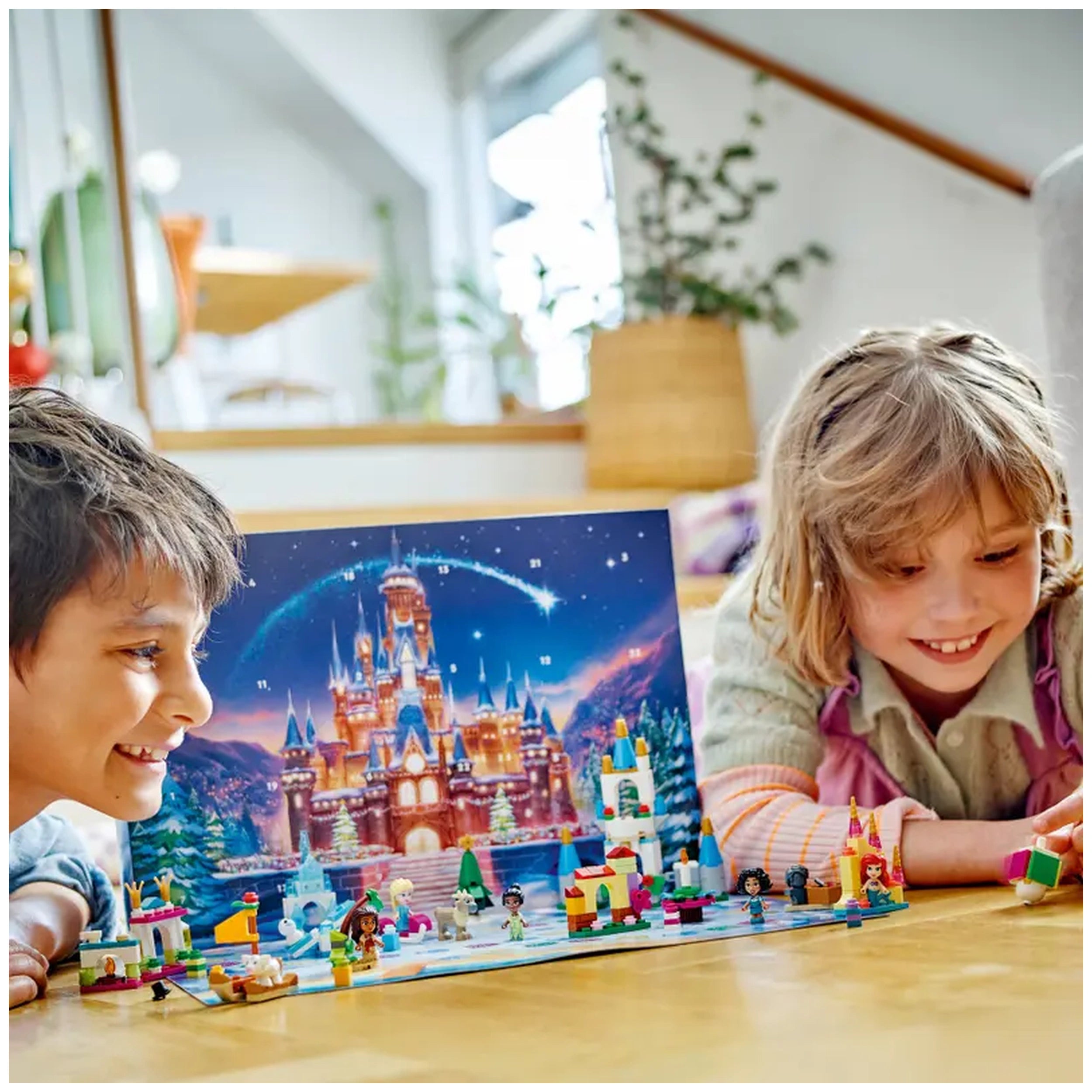 Two children crouch on a wooden floor, joyfully engaged with the LEGO® Disney Advent Calendar, featuring a magical castle backdrop and colorful mini builds. The boy smiles widely, while the girl examines a LEGO piece, surrounded by cheerful Disney characters. Soft natural light fills the room, highlighting their excitement.