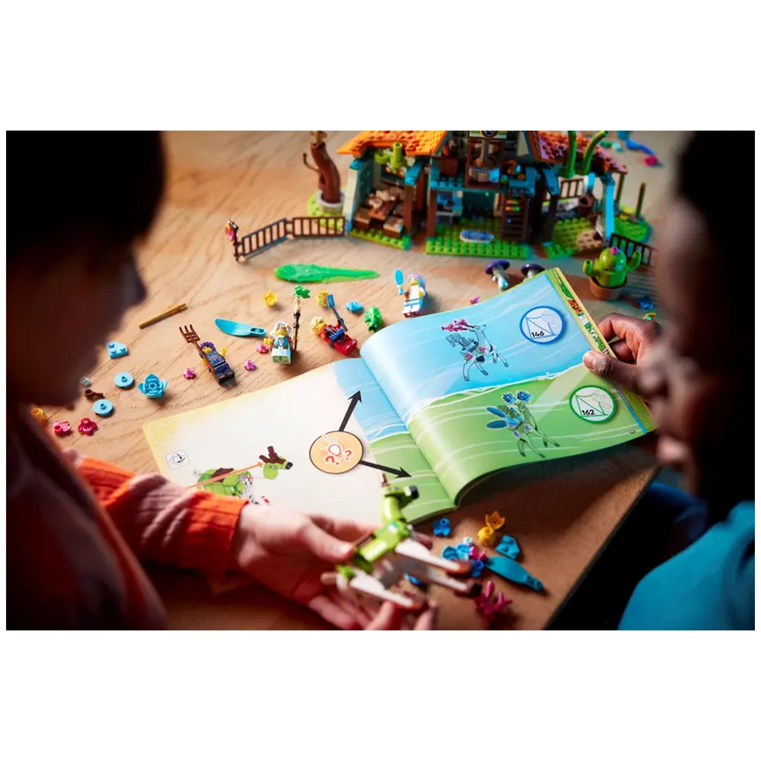 Two children engaged in play, one holding a green LEGO creature while the other studies a colorful instruction booklet, surrounded by scattered building pieces and the LEGO Stable of Dream Creatures in the background.