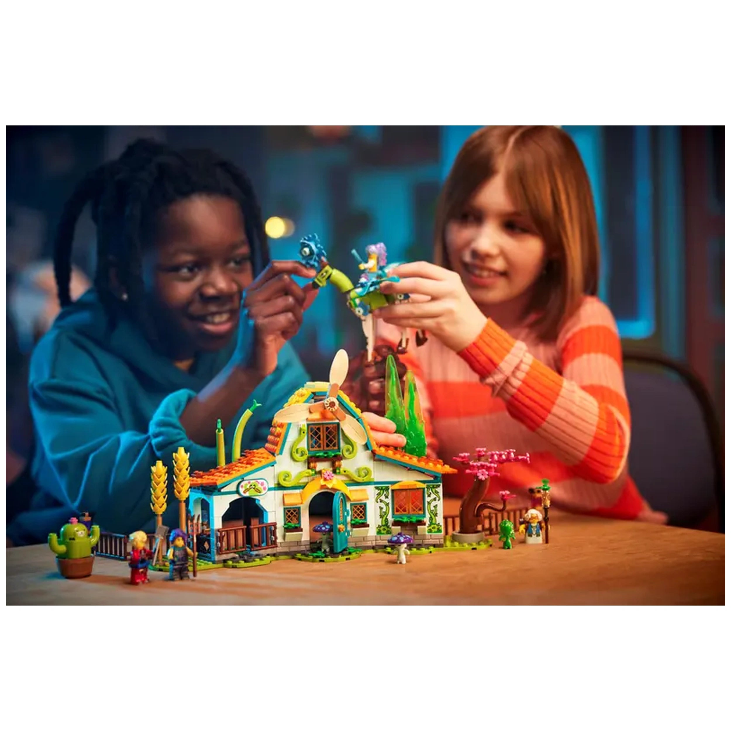 Two children joyfully playing together with the LEGO® DREAMZzz™ Stable of Dream Creatures construction set, featuring a colorful barn and whimsical elements.