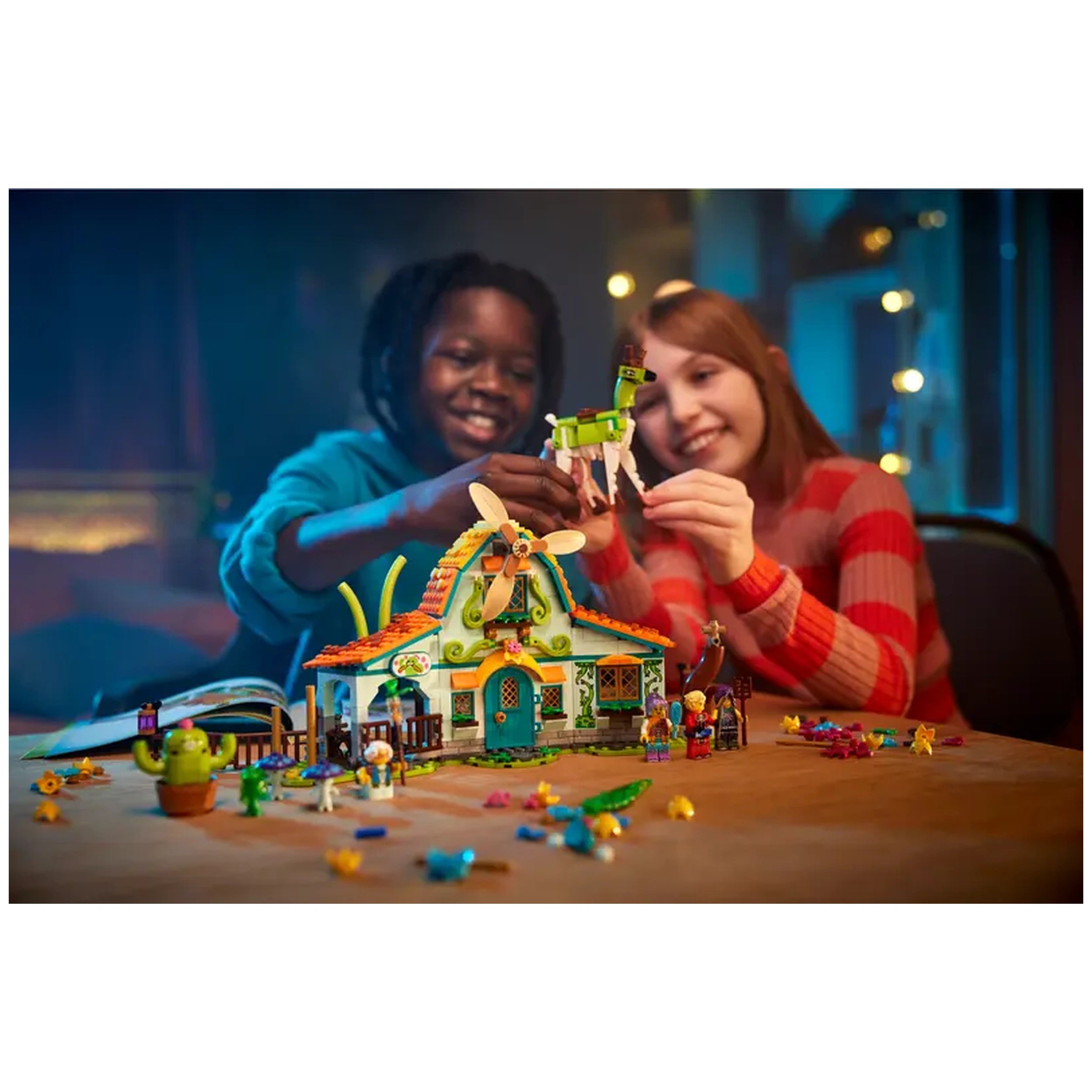 Two children excitedly play with the LEGO® DREAMZzz™ Stable of Dream Creatures set, featuring a colorful barn and whimsical figures, including a green creature. Brightly lit background creates a warm atmosphere, enhancing their imaginative play.