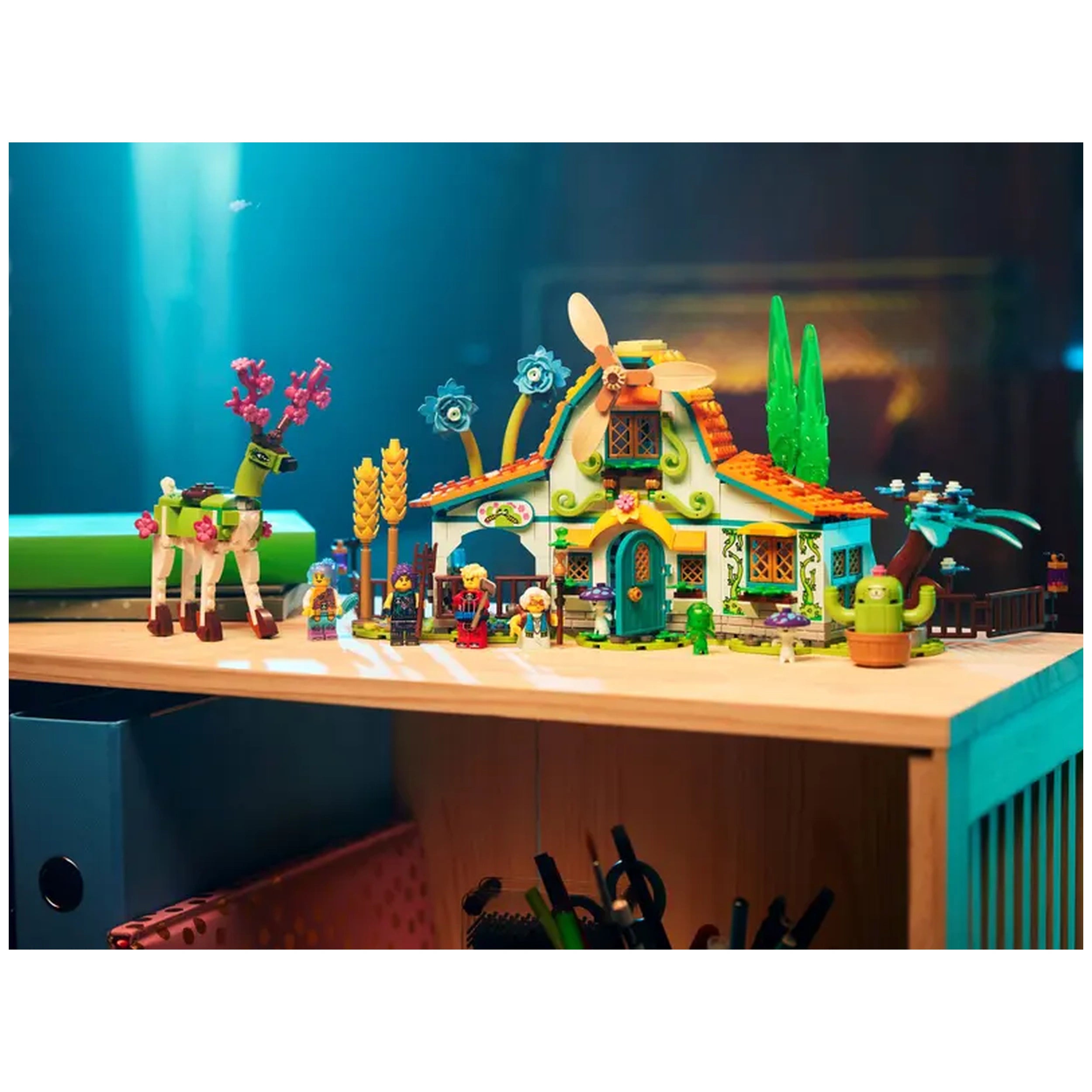 Colorful LEGO® DREAMZzz™ Stable of Dream Creatures set on a wooden table, featuring a whimsical house, playful figures, and a green deer with flowers.