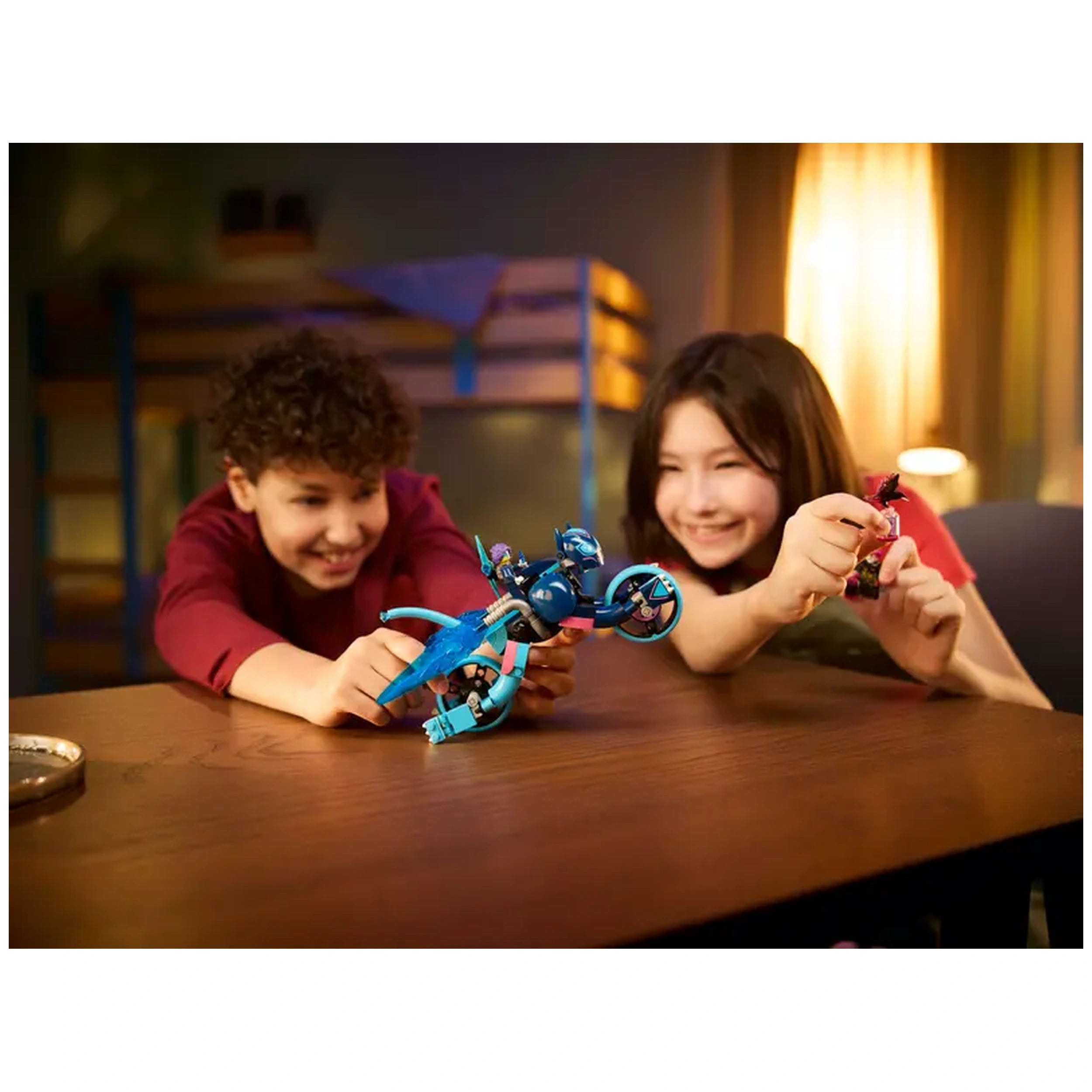 Two children joyfully play with LEGO® DREAMZzz™ Zoey’s Cat Motorcycle set on a wooden table, showcasing creativity and fun.