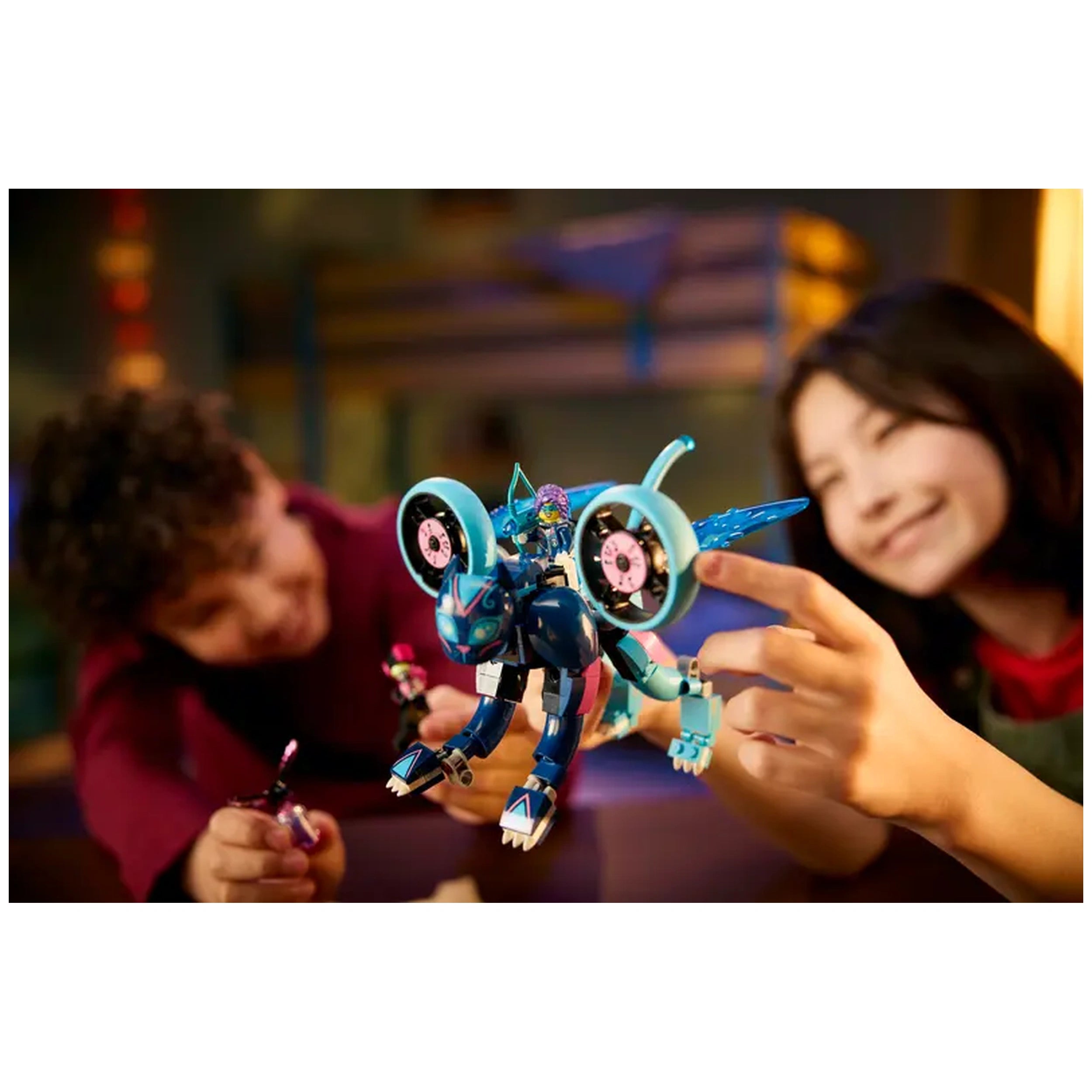Two children eagerly interact with a colorful LEGO® set featuring a blue cat motorcycle. One child, with curly hair, holds a small figure while the other points to the motorcycle, showcasing fun and creativity. The vibrant scene captures the excitement of imaginative play inspired by the DREAMZzz™ series.