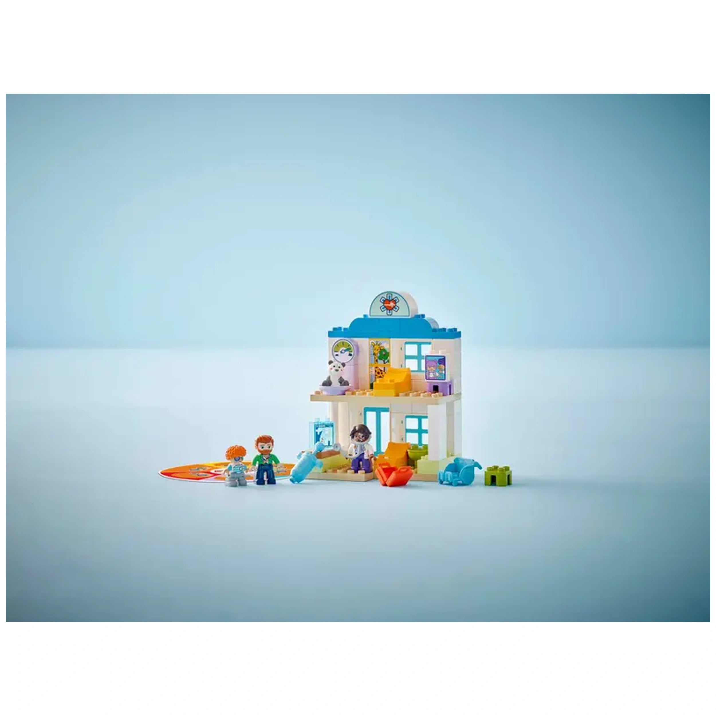 Colorful LEGO® DUPLO® Town playset featuring a two-story hospital, with four figures: a child, adult, doctor, and teddy bear.