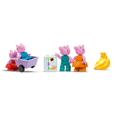 Four playful Peppa Pig characters, including Peppa and George, engage at a colorful supermarket scene, with a toy cart and food items nearby.