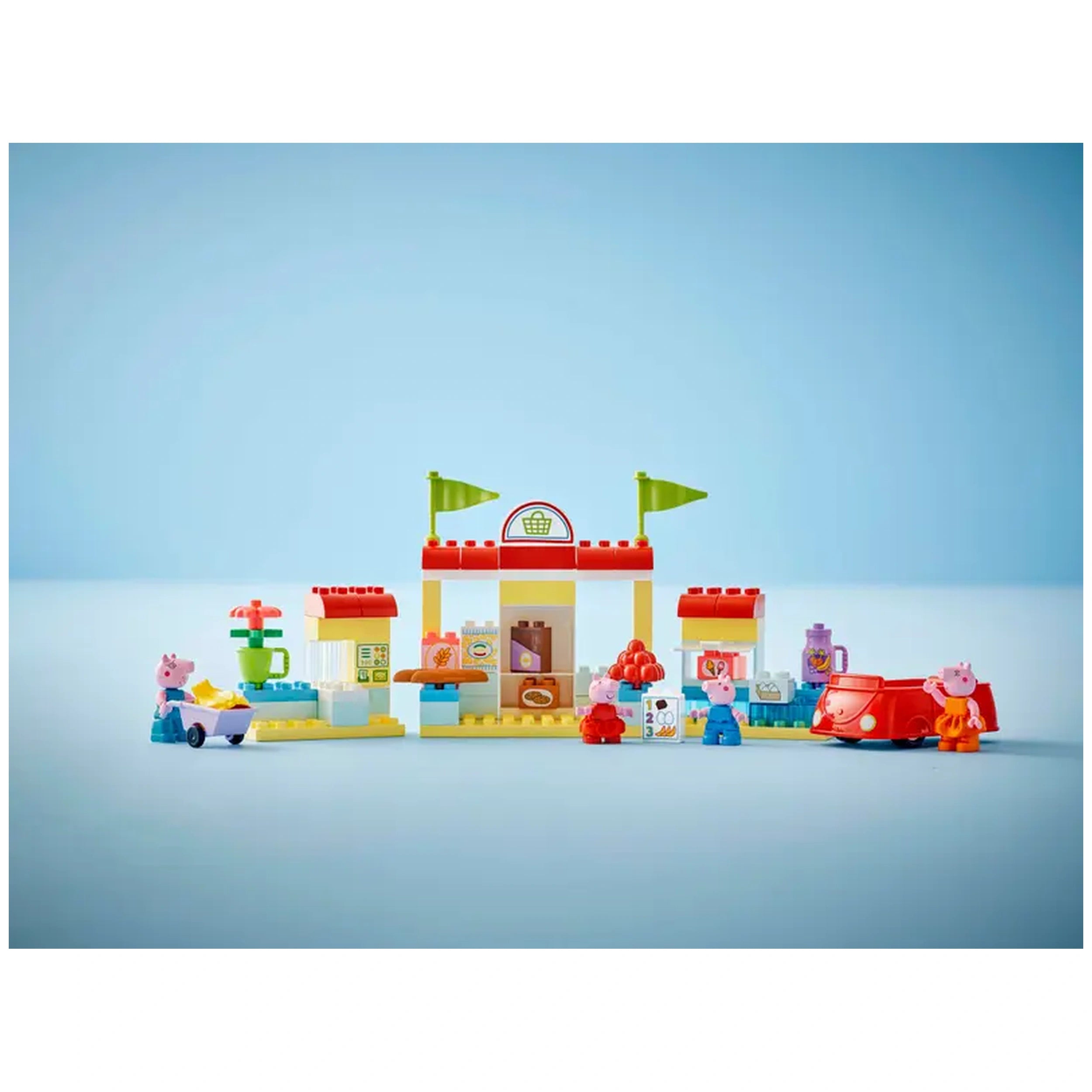 LEGO® DUPLO® Peppa Pig Supermarket set featuring colorful structures, grocery items, and four characters: Peppa, George, Mummy Pig, and Daddy Pig with a red car.