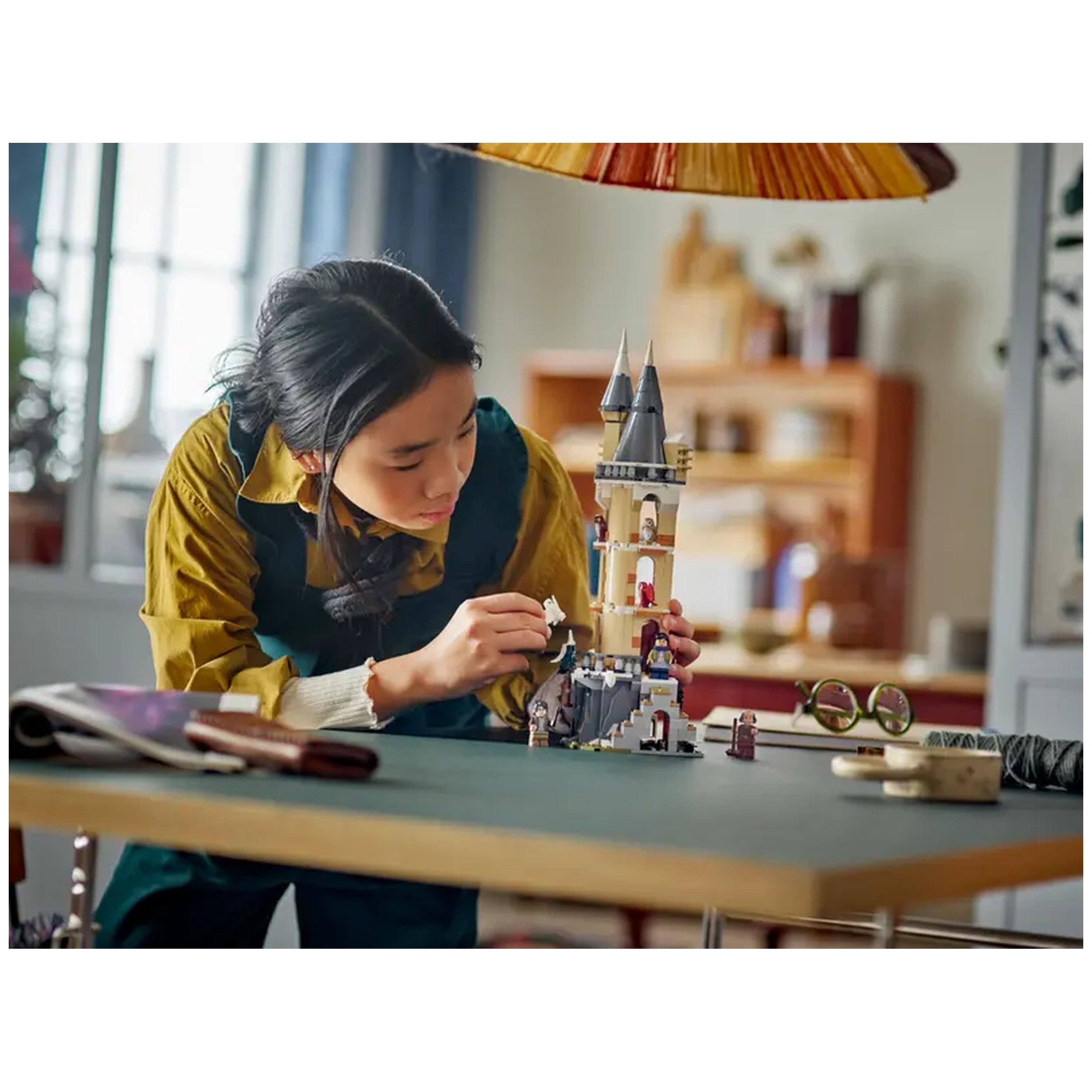 A child concentrates on assembling the LEGO Harry Potter Hogwarts Castle Owlery set, showcasing its detailed tower and characters.