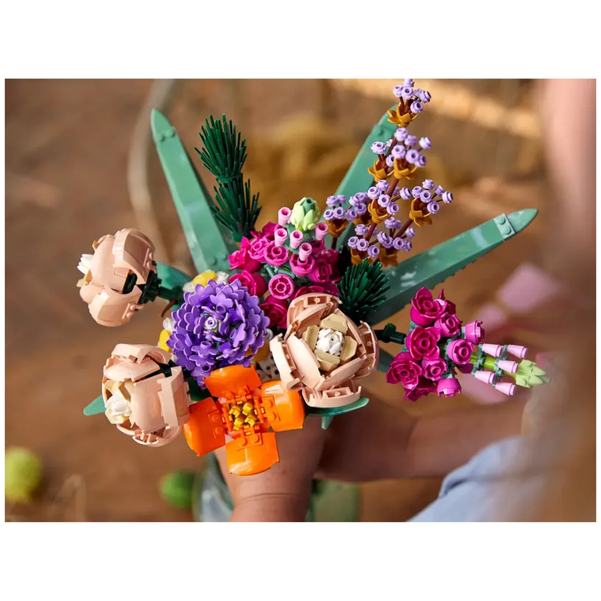 Colorful LEGO Flower Bouquet featuring pink roses, purple asters, and orange blooms, held in a hand against a wooden background.