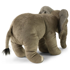 Eco-friendly plush elephant toy in gray and brown, featuring large floppy ears and a tufted tail, standing upright.