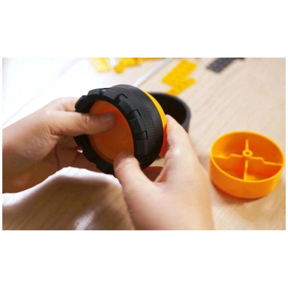 Child assembling an orange and black wheel from the Alexander Constructor Pro Metal Scratch 7 in 1 set on a wooden table.