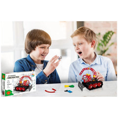 Two children excitedly assembling Alexander Constructor Snow Cat with colorful pieces on a white table.