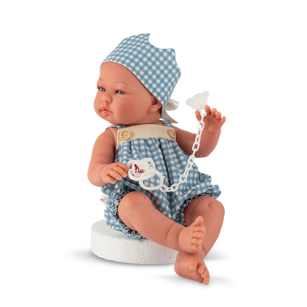 ASI Dolls - Pablo and Maria Vinyl Dolls dressed in a blue and white checkered outfit, seated with a pacifier in hand.
