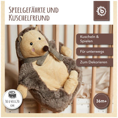 Piksi the Hedgehog, a soft stuffed animal with a chocolate and oatmeal color scheme, rests against wooden crib bars, exuding warmth and charm.